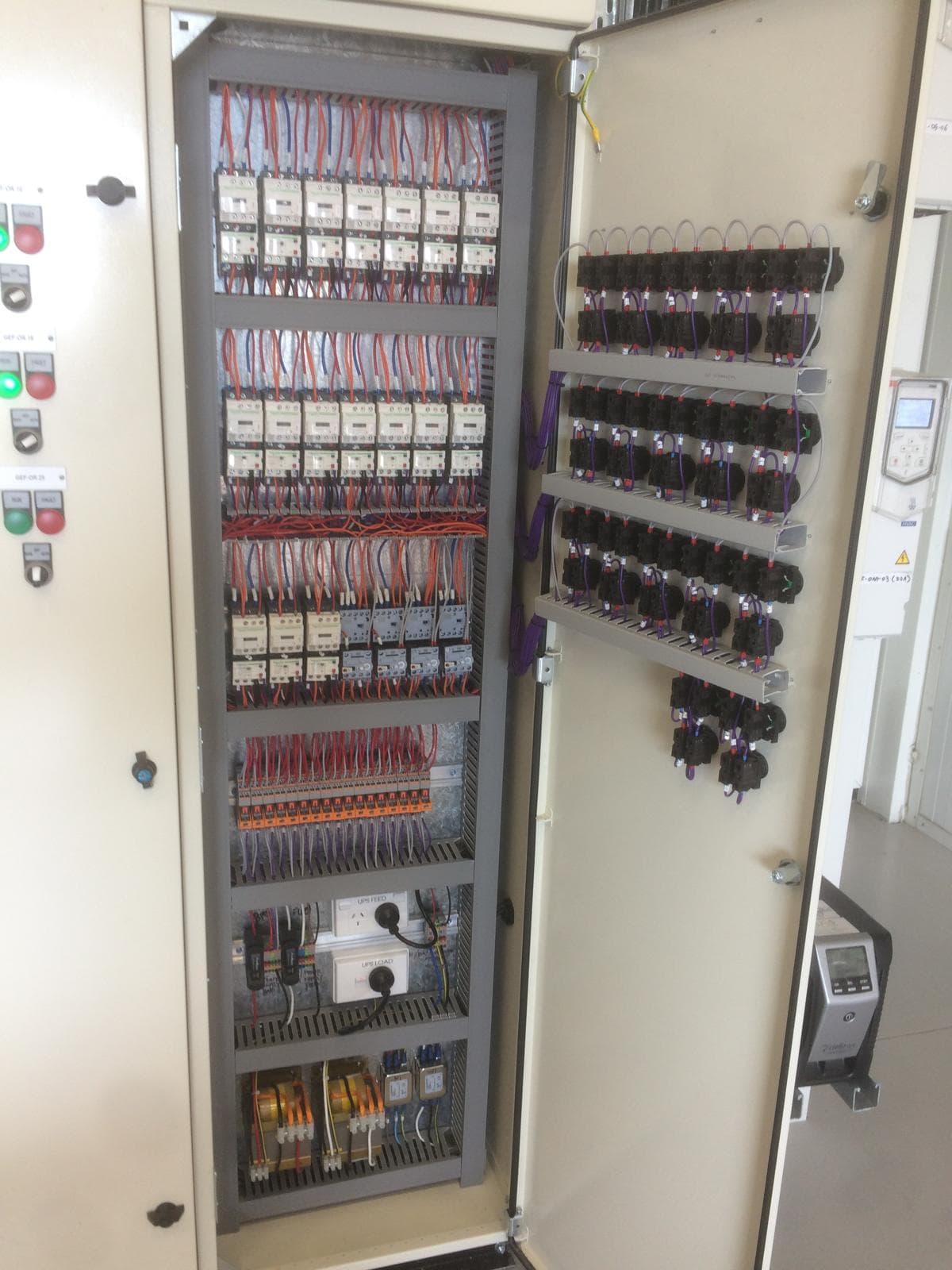 Open electrical cabinet showing door-mounted control wiring and terminal wiring